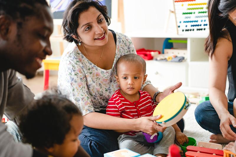 Parents sitting together with their children, playing with musical instruments.