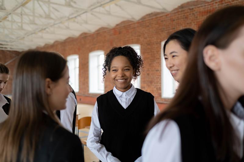 young women smiling at each other in school uniform