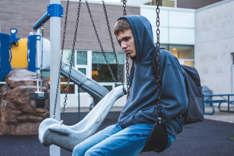 Young man sits in child's playground