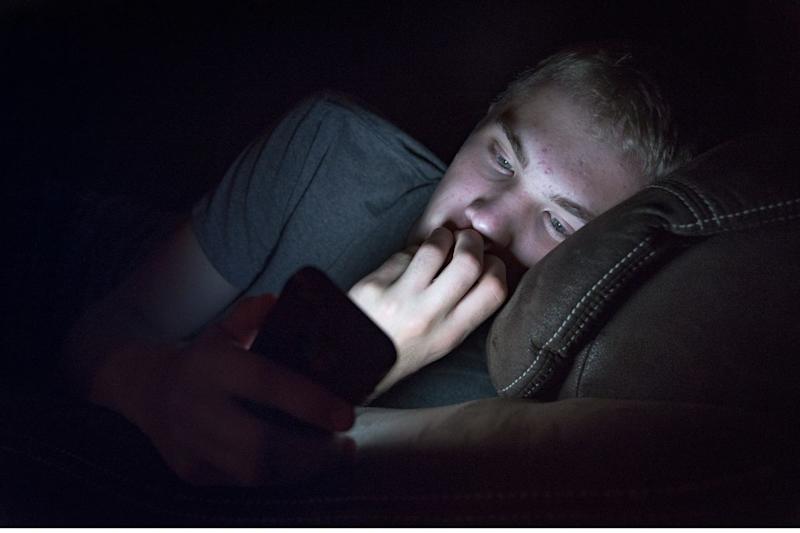 Young male lying down looking at his phone.