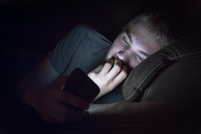 Young male lying down looking at his phone.