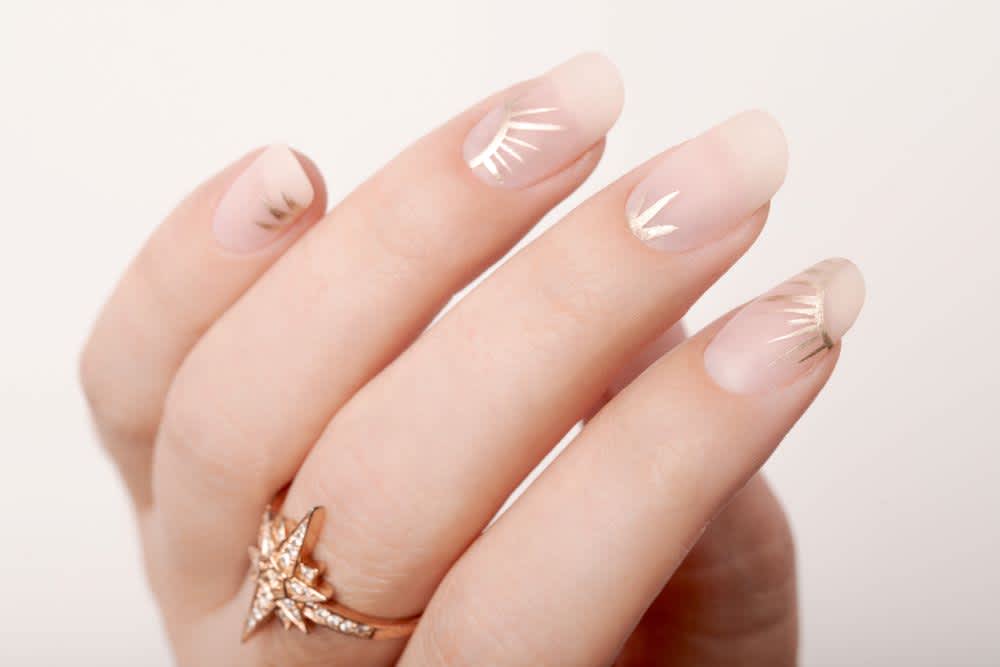 nude matte nails with gold metallic sunbursts 