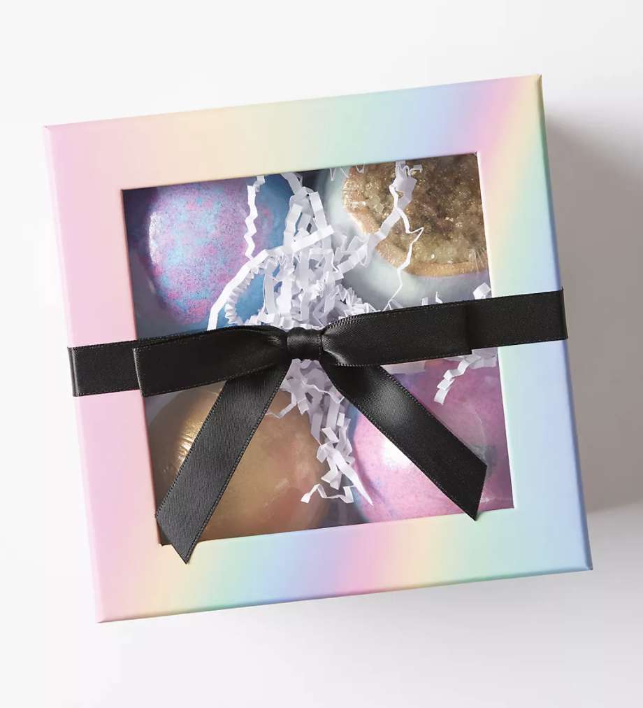 Rainbow colored box with a black ribbon tied into a bow with four fizz bath balls inside