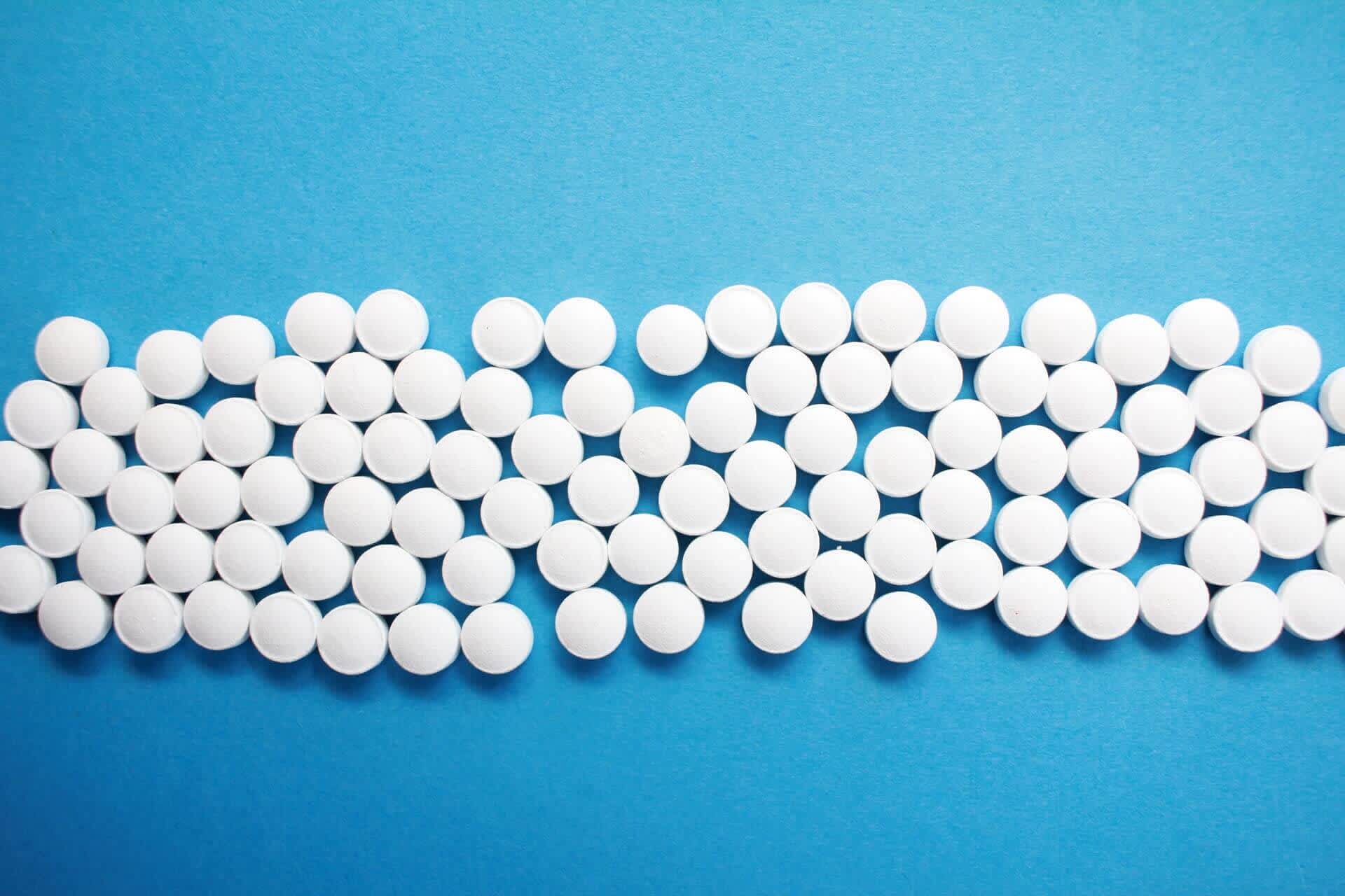 Round claritin white pills with blue background
