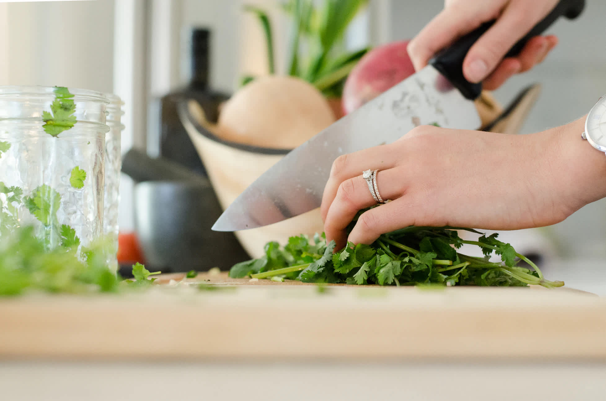 Female chopping cilantro with a chef’s knife.