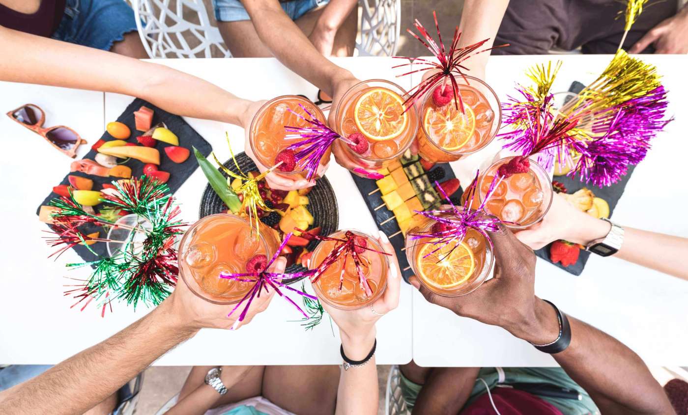 Friends hands toasting " Sex on the Beach " fancy drinks
