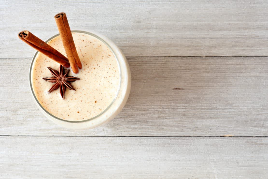 Top view on a rustic gray wood background of Christmas spiced eggnog in a glass