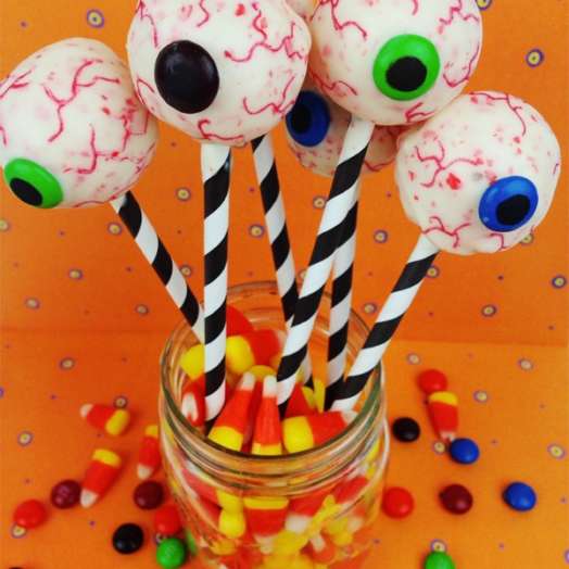 Eyeball cake pops on sticks in a mason jar filled with candy corn