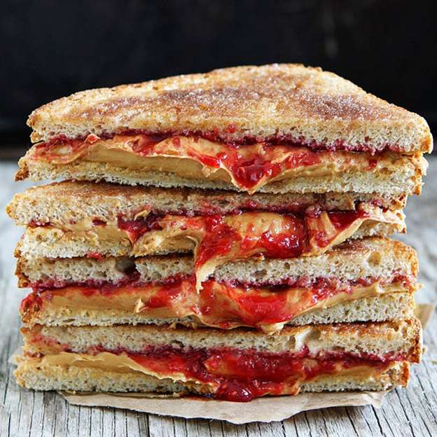 Cinnamon toast peanut butter and jelly sandwich halves stacked on a plate