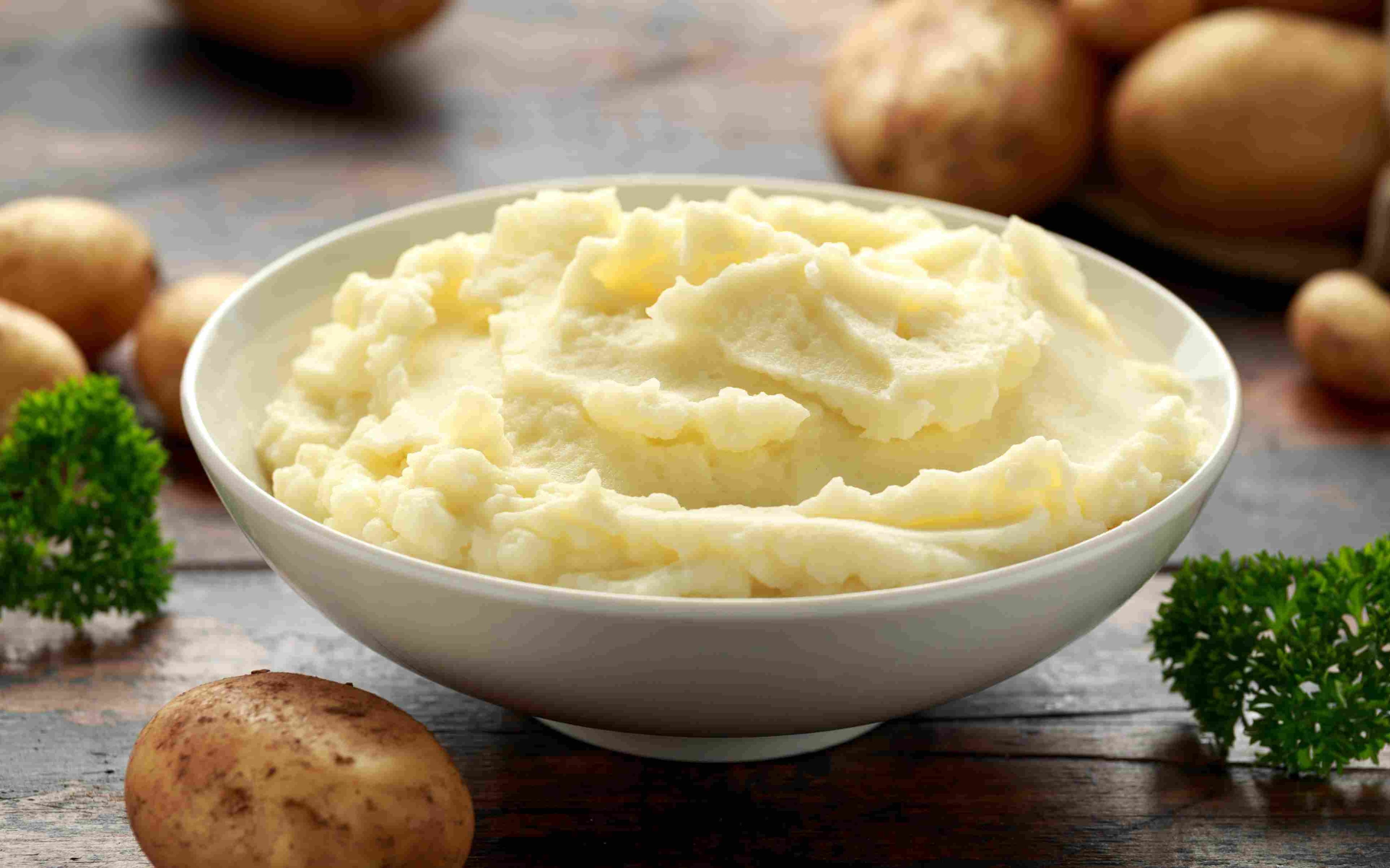 Mashed potatoes in white bowl on wooden rustic table