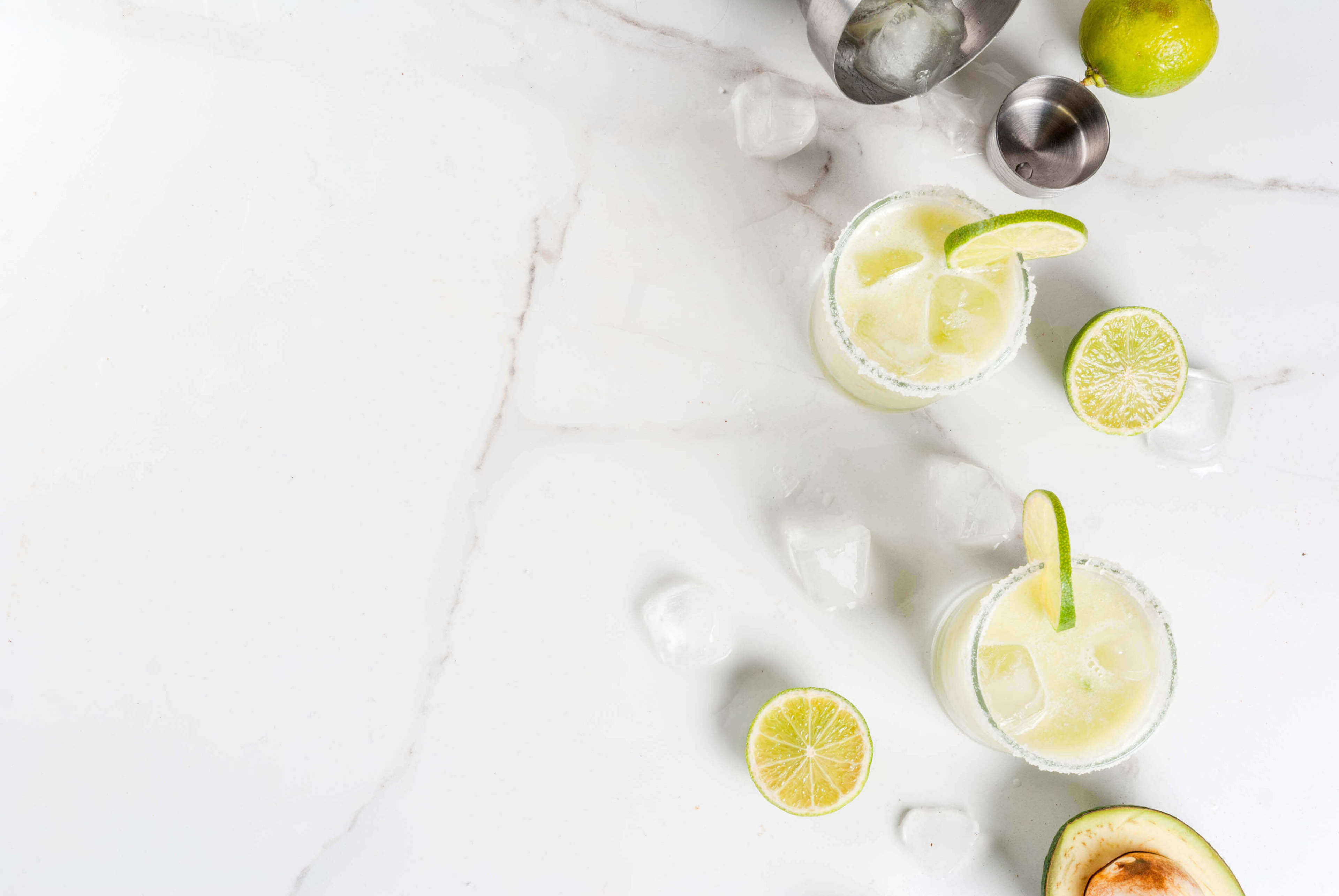 Avocado and lime margarita with salt, on a white marble kitchen table