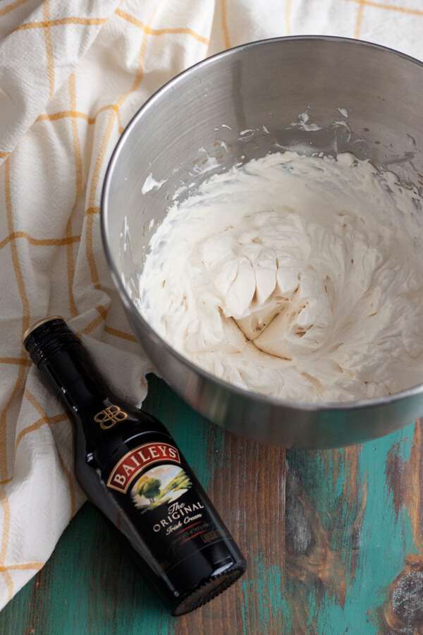 A bottle of Baileys Irish Cream Liqueur and bowl of whipped cream