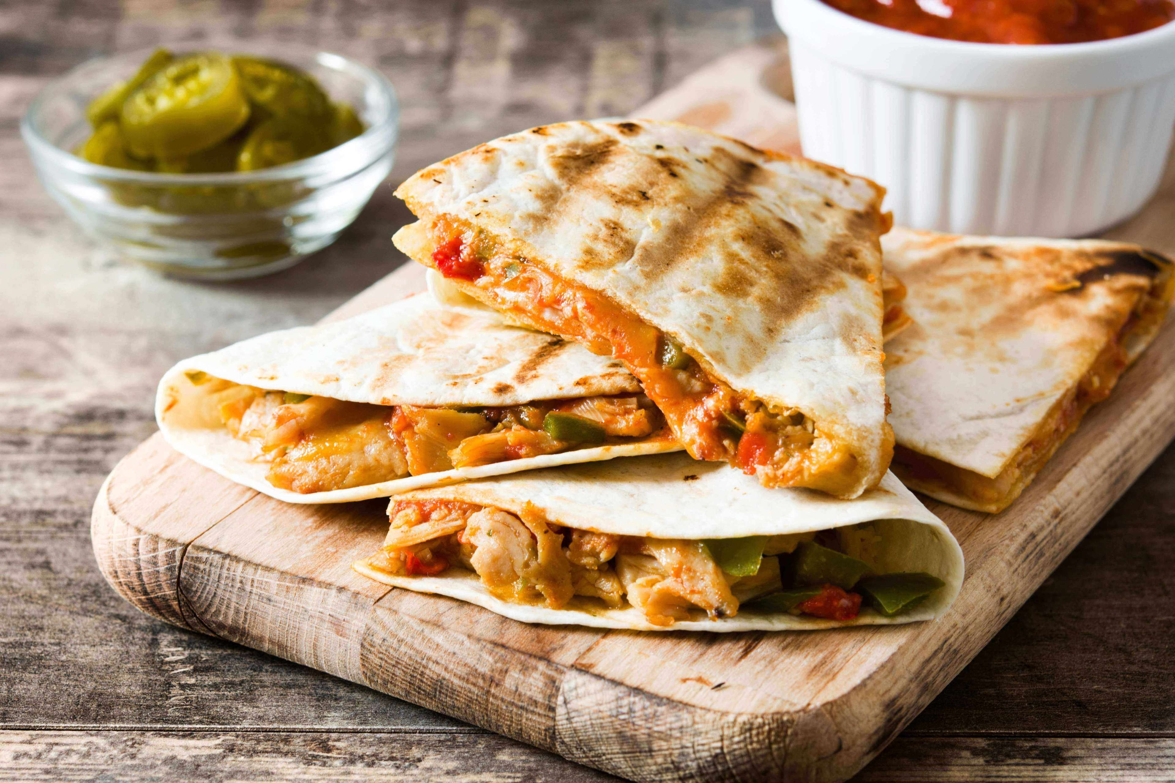 Mexican quesadilla with chicken, cheese and peppers on wooden table