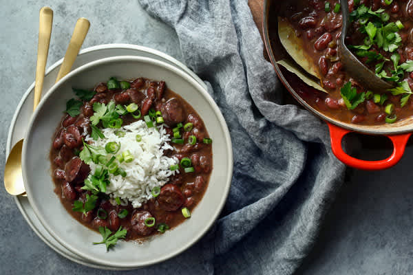Red beans and rice that’s garnished with green onions and parsley served in a bowl 