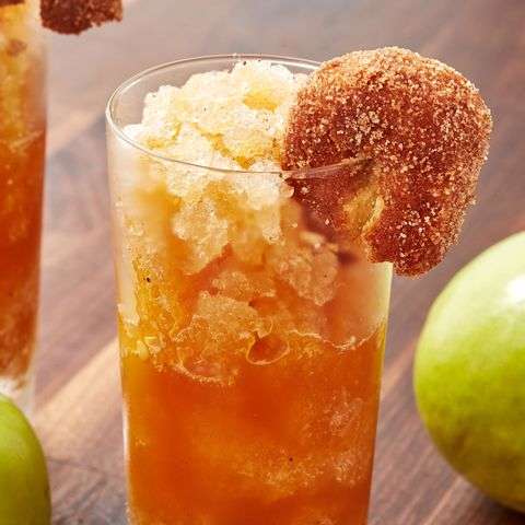 An apple cider slushie served in a highball glass and garnished with a cinnamon and sugar doughnut
