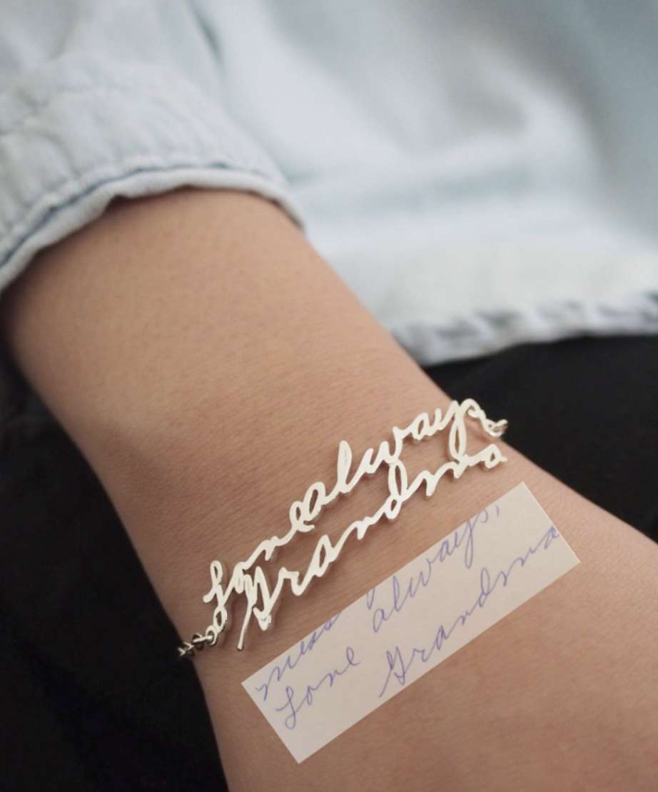 A wrist with a silver bracelet on with a piece of handwriting under it