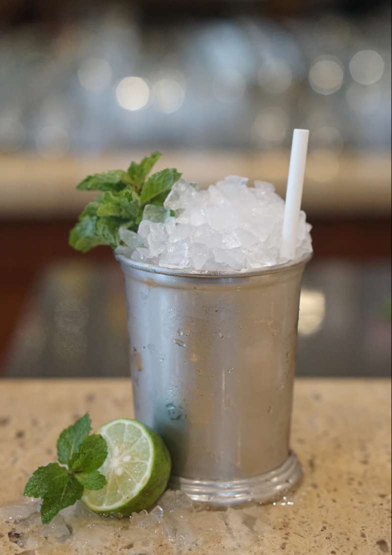 Mint julep in a silver mug overflowing with ice and garnished with mint leaves.