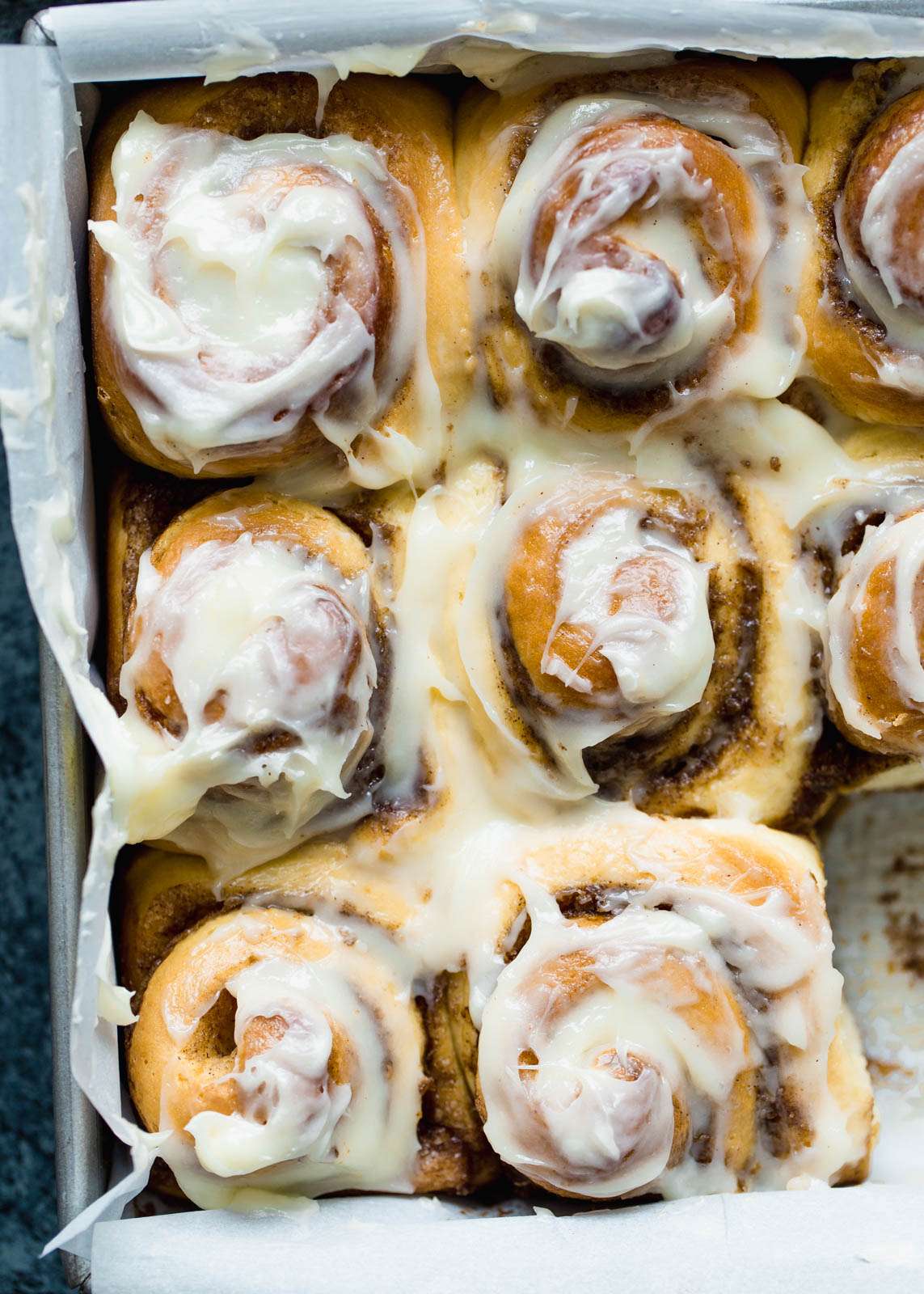A tray of baked cinnamon rolls covered in a creamy vanilla glaze.