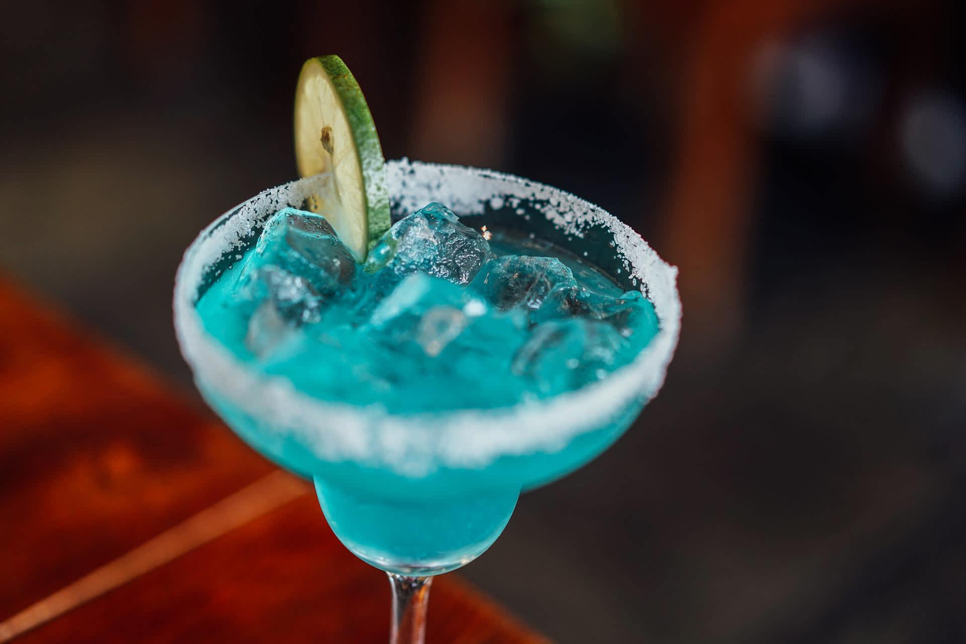 Blue margarita in a cup with a slice of lemon on top