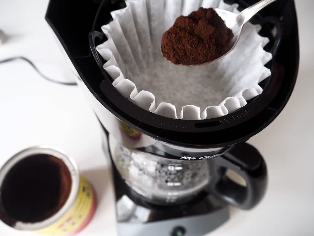 Person putting espresso grounds into a drip coffee maker 