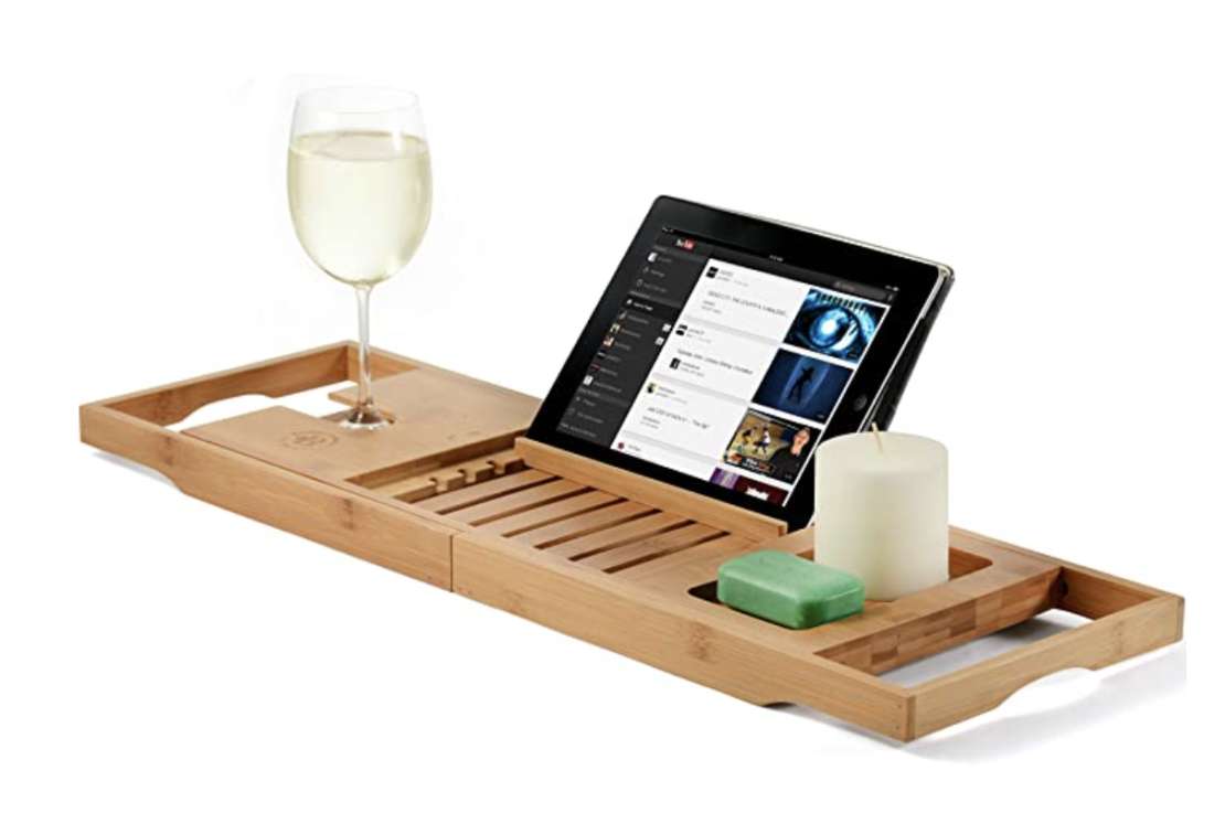 Bamboo bathtub caddy tray with an iPad, glass of white wine and a candle on it