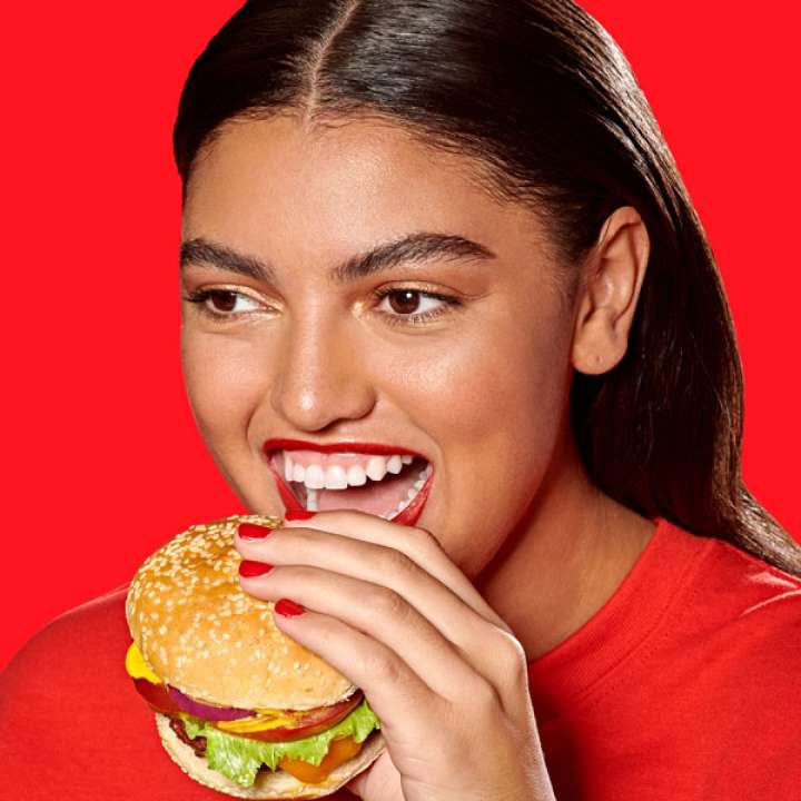 Woman in red t-shirt eating hamburger