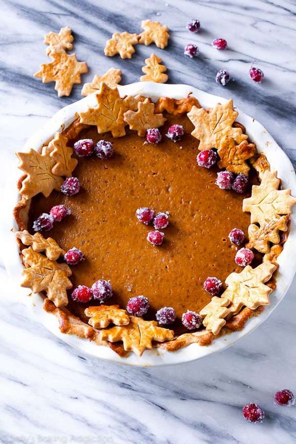 A delicious looking pumpkin pie on a marble surface, topped with berries