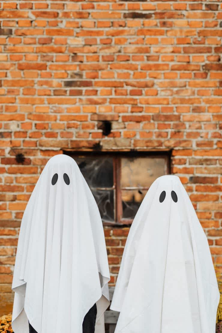 Two sheet ghosts against a brick wall