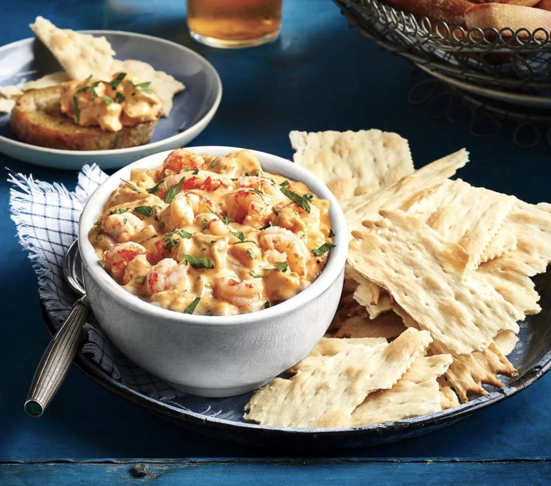 Crawfish dip in a bowl served with a plate of crackers