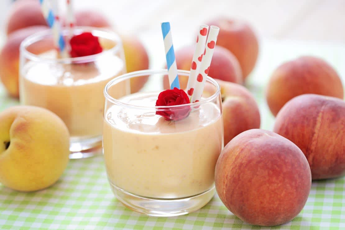 Peach smoothie glasses with peaches on table