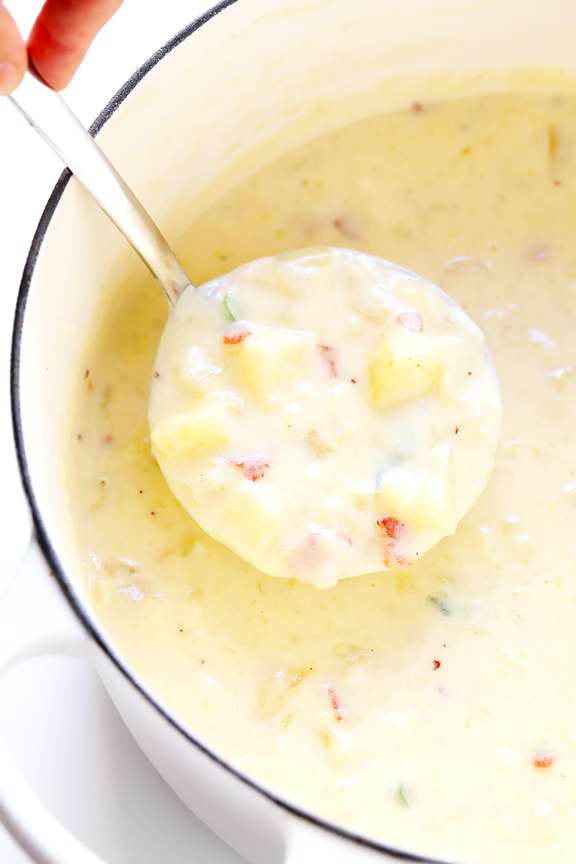 A spoonful of potato soup taken from a bowl of potato soup