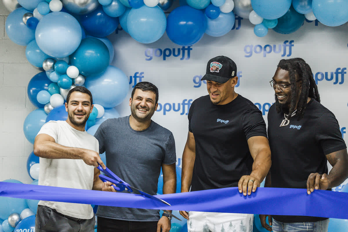 Gopuff co-founders and co-CEO’s Rafael ilishayev and Yakir Gola, standing with DeMarcus Lawrence and Tyrone Crawford in front of a white backdrop and a blue balloon arch.