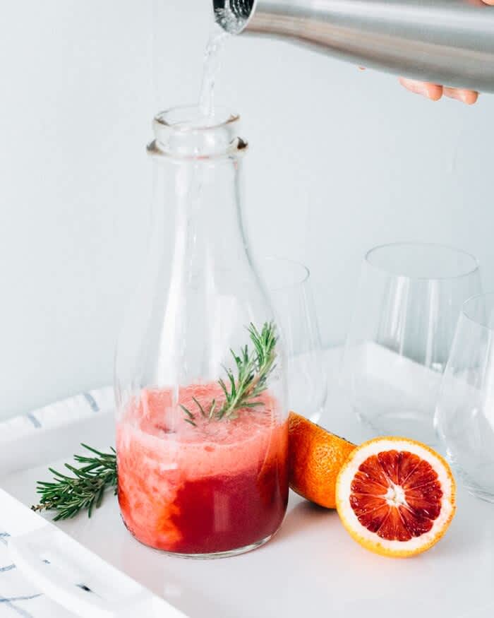 Glass milk jar with sparkling blood orange rosemary water