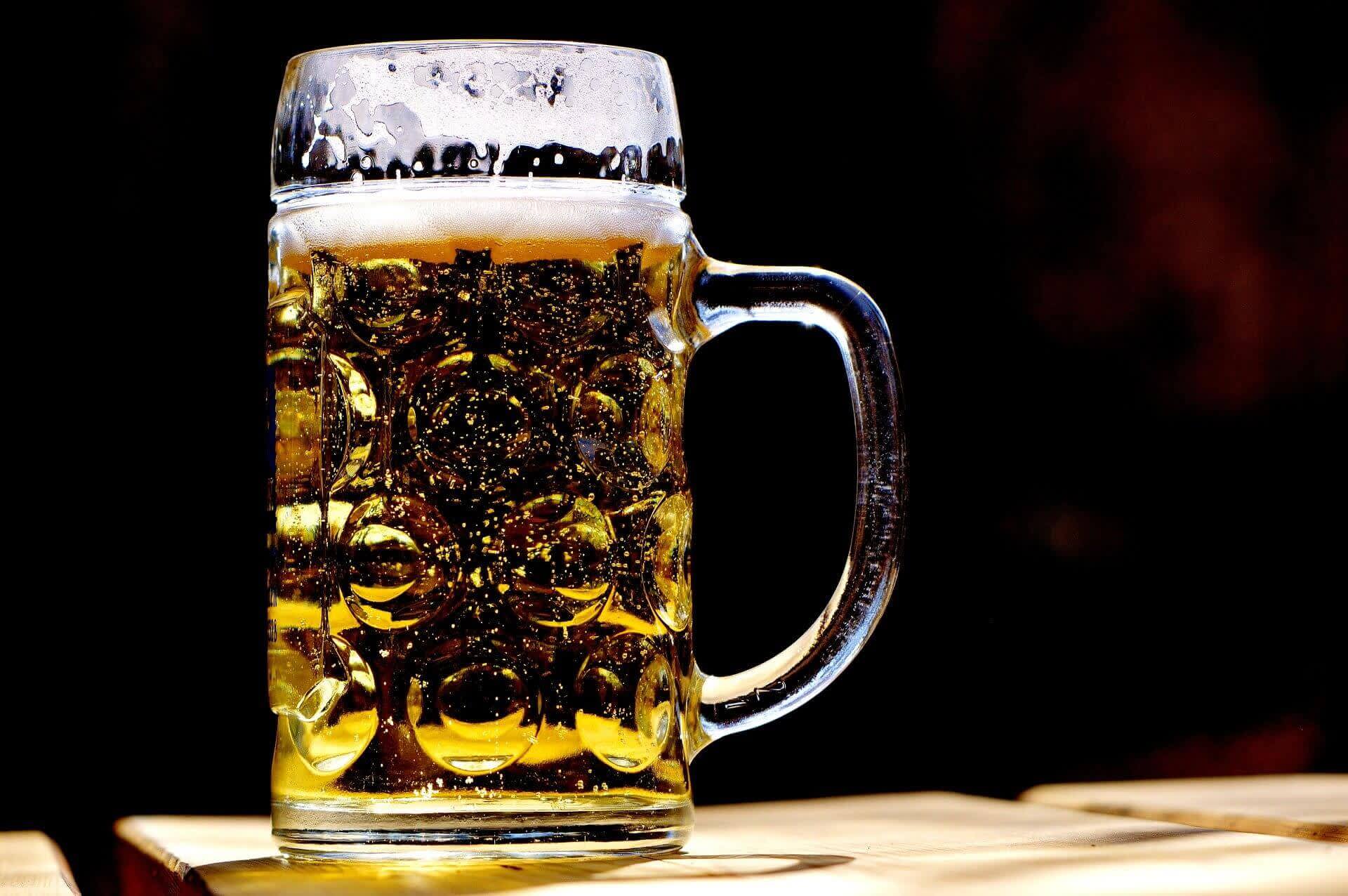 Beer mug with foam on table over black background