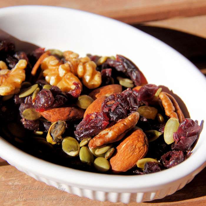 Snack mix with cranberries, pumpkin seeds and brazil nuts in a white ceramic dish