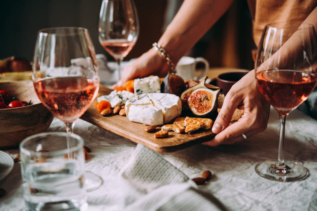 Woman setting the table for dinner with cheeseboard and wine