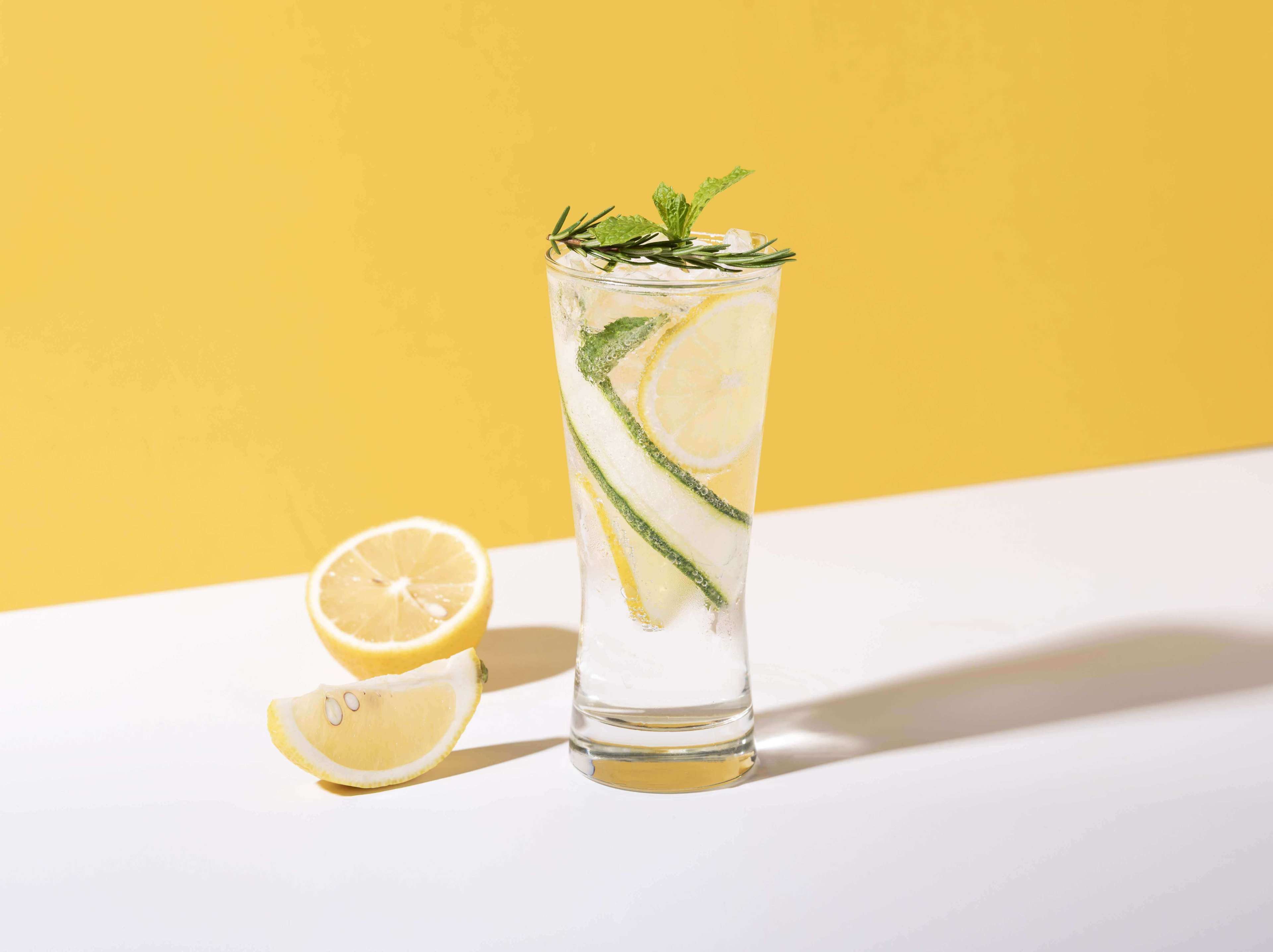 Mojito cocktail with lemon and mint in glass on yellow background