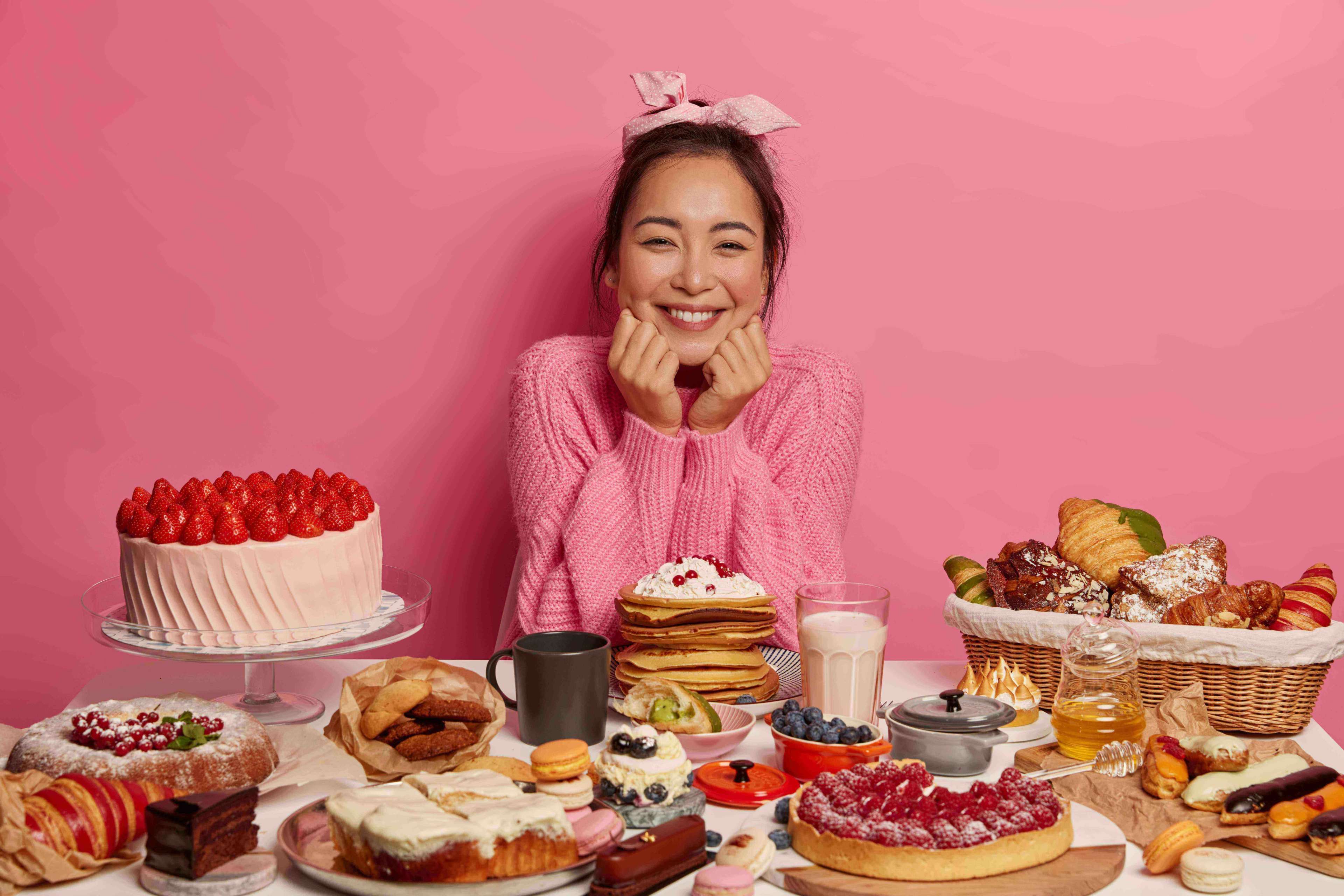 Woman smiling with desserts and food infront