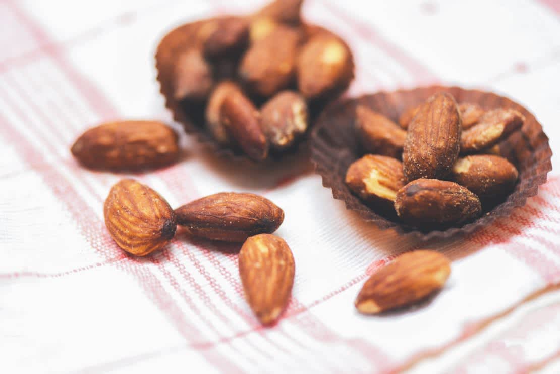 Close up of roasted almonds in a cup on tablecloth