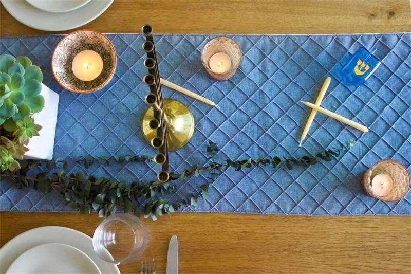 Overhead view of a table set for Hanukkah with menorah, candles, table runner and dishes