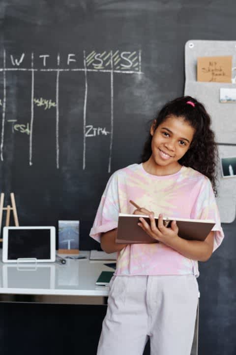 Student writing on a notebook in a classroom