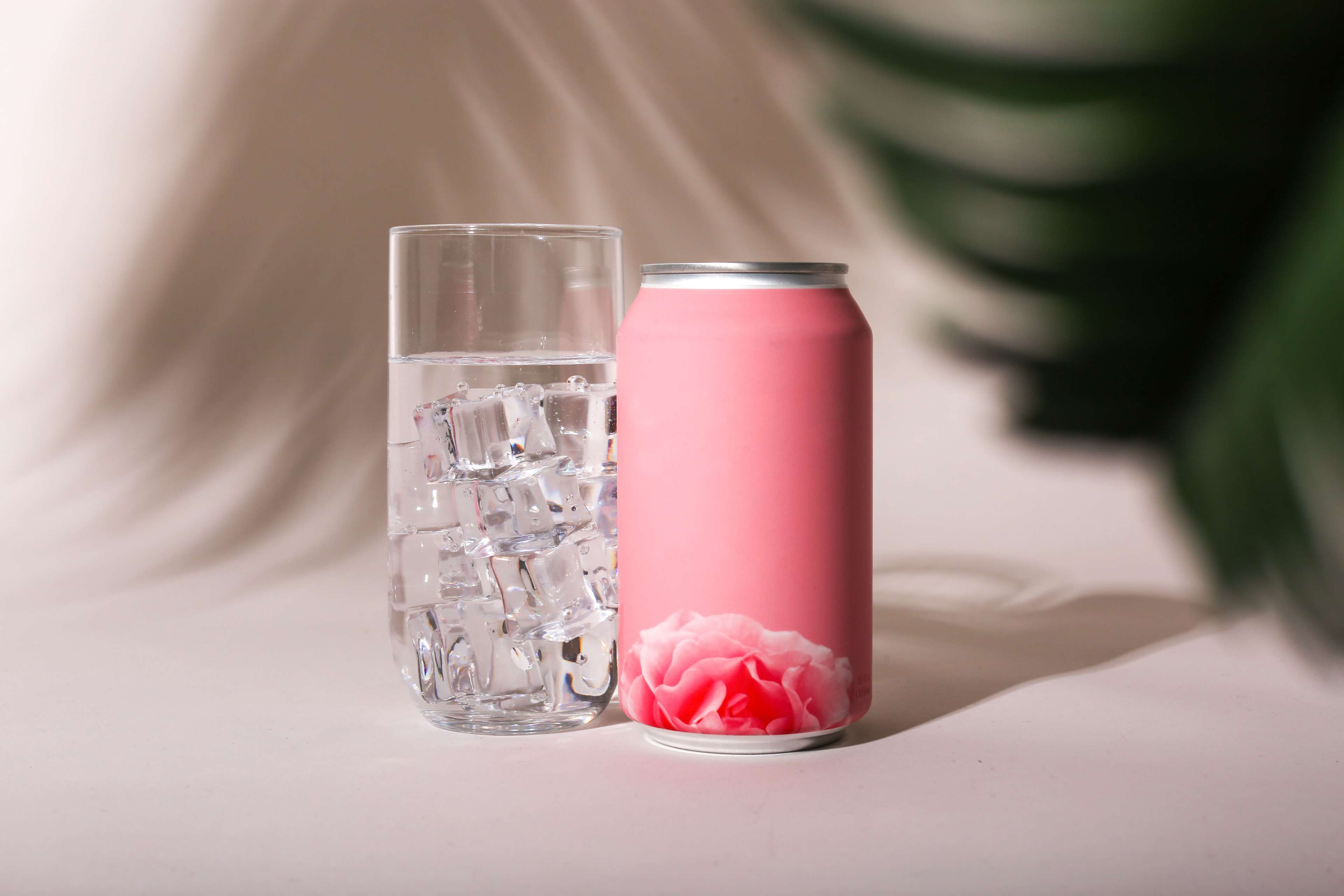 Pink non-carbonated drink with flower drawing next to glass with liquid and ice