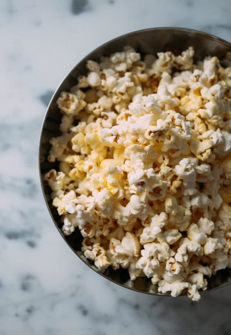 Black bowl full of popcorn on top of a marble countertop