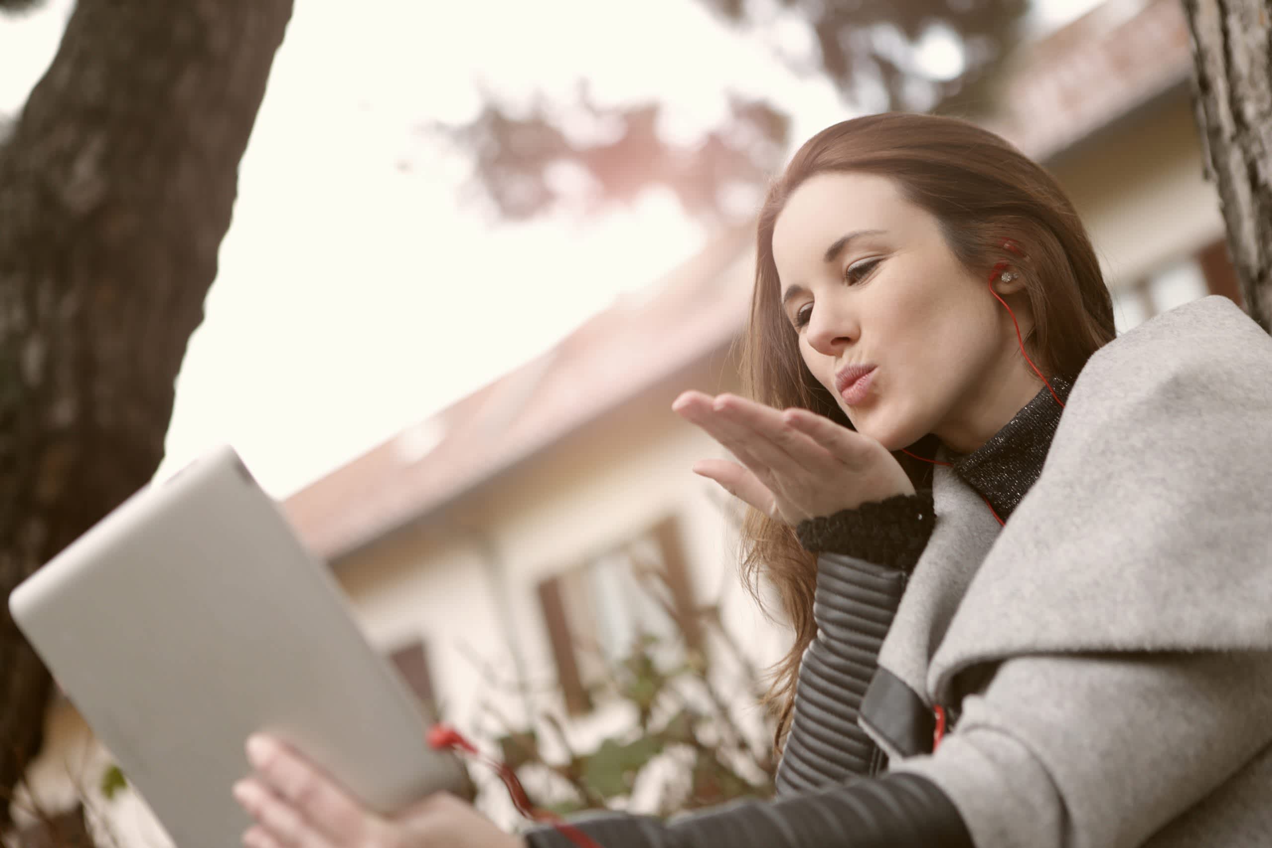 Woman with laptop video chatting and blowing a kiss