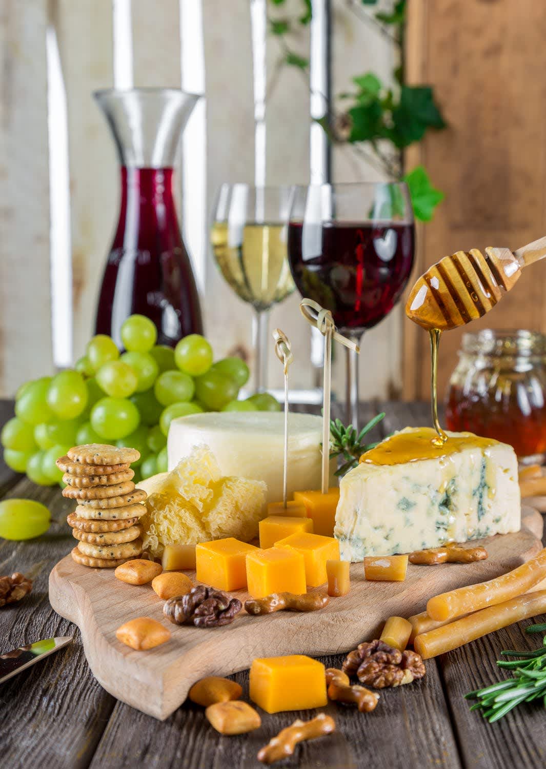 A spread of various cheeses with red and white wines