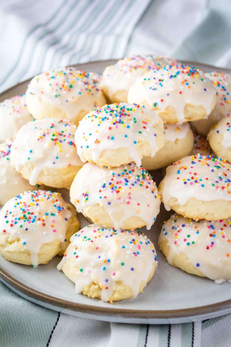 Plate of Italian ricotta cookies topped with glaze and sprinkles.