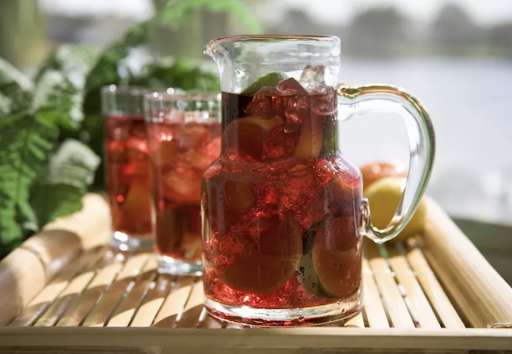 A pitcher of low sugar red sangria with two glasses behind it
