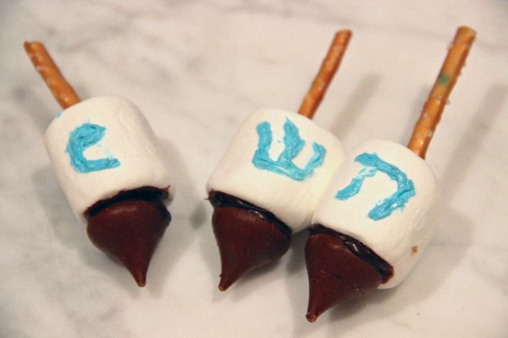 3 edible dreidels made with marshmallows, pretzel sticks, frosting and Hershey Kisses