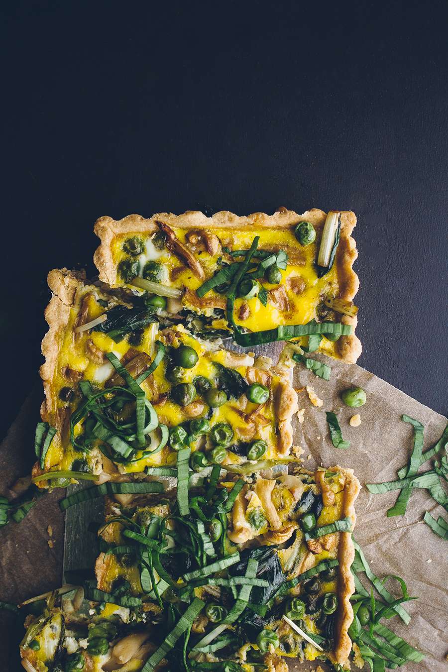 Quiche with vegetables garnished with ramp slices.