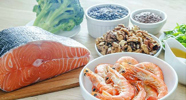 Salmon steak, a bowl of shrimp and other foods containing healthy fats like omega-3